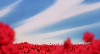 Movie still from “Revolutionary Girl Utena: The Movie” (1999), directed by Katsushi Sakurabi – A field full of red flowers under a blue sky; Extreme Wide shot, Low angle