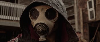 Movie still from “Rhymes for Young Ghouls” (2013), directed by Jeff Barnaby – A person wearing a gas mask with a hood on; Close Up shot, Low angle