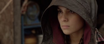 Movie still from “Rhymes for Young Ghouls” (2013), directed by Jeff Barnaby – A young woman wearing a hooded jacket and a hat; Close Up shot, Over the shoulder angle