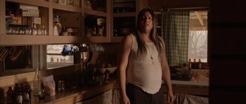 Movie still from “Rhymes for Young Ghouls” (2013), directed by Jeff Barnaby – A man standing in a kitchen wearing a white shirt; Medium shot, Over the shoulder angle