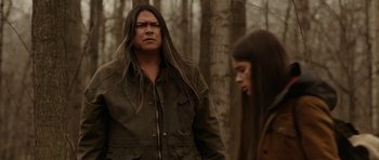 Movie still from “Rhymes for Young Ghouls” (2013), directed by Jeff Barnaby – A man and a woman standing next to each other in the woods; Medium shot, Over the shoulder angle