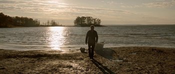 Movie still from “Rhymes for Young Ghouls” (2013), directed by Jeff Barnaby – A man walking on the beach near the water; Wide shot, High angle