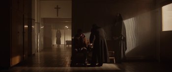 Movie still from “Rhymes for Young Ghouls” (2013), directed by Jeff Barnaby – A group of people standing around in a room; Wide shot, Low angle