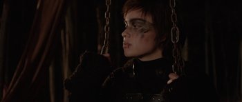 Movie still from “Rhymes for Young Ghouls” (2013), directed by Jeff Barnaby – A young man with makeup on his face is sitting on a swing; Close Up shot, Over the shoulder angle
