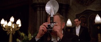 Movie still from “Richard III” (1995), directed by Richard Loncraine – An older man taking a picture with a camera; Close Up shot, Low angle