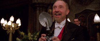 Movie still from “Richard III” (1995), directed by Richard Loncraine – An older man in a tuxedo holding a camera and smiling; Close Up shot, Low angle