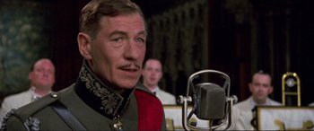 Movie still from “Richard III” (1995), directed by Richard Loncraine – A person with a microphone; Close Up shot, Low angle