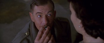 Movie still from “Richard III” (1995), directed by Richard Loncraine – A man is putting something in his mouth; Close Up shot, Over the shoulder angle
