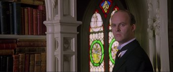 Movie still from “Richard III” (1995), directed by Richard Loncraine – A man standing in front of a stained glass window; Close Up shot, Low angle