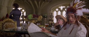 Movie still from “Richard III” (1995), directed by Richard Loncraine – A young man reading a newspaper at a table; Medium shot, Over the shoulder angle