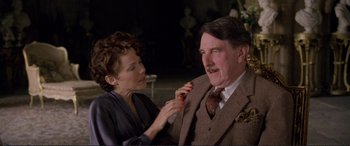 Movie still from “Richard III” (1995), directed by Richard Loncraine – An older man in a suit and a young woman in a dress; Medium shot, Low angle