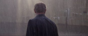 Movie still from “Richard III” (1995), directed by Richard Loncraine – A man standing in the pouring rain with his back to the camera; Medium shot, Over the shoulder angle