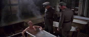 Movie still from “Richard III” (1995), directed by Richard Loncraine – A man sitting in a bath tub next to two other men; Wide shot, High angle