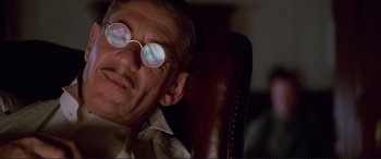 Movie still from “Richard III” (1995), directed by Richard Loncraine – An older man wearing glasses sitting in a leather chair; Close Up shot, Low angle