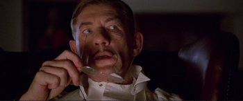 Movie still from “Richard III” (1995), directed by Richard Loncraine – An older man holding a cell phone up to his ear; Close Up shot, Low angle