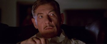 Movie still from “Richard III” (1995), directed by Richard Loncraine – An older man looking at the camera while sitting down; Close Up shot, Low angle