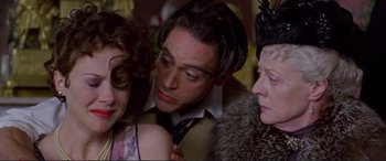 Movie still from “Richard III” (1995), directed by Richard Loncraine – A man and two women are standing next to each other; Close Up shot, Over the shoulder angle