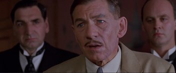 Movie still from “Richard III” (1995), directed by Richard Loncraine – An older man in a suit and tie looking to his left; Close Up shot, Low angle