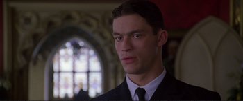 Movie still from “Richard III” (1995), directed by Richard Loncraine – A man in a suit and tie looking at the camera; Close Up shot, Low angle