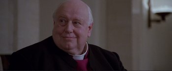 Movie still from “Richard III” (1995), directed by Richard Loncraine – An older man wearing a priest's outfit and smiling; Close Up shot, Low angle