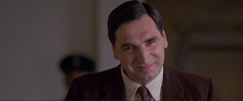 Movie still from “Richard III” (1995), directed by Richard Loncraine – A man in a suit and tie looking at the camera; Close Up shot, Low angle