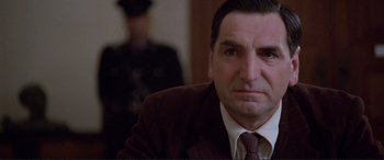 Movie still from “Richard III” (1995), directed by Richard Loncraine – A person wearing a suit and tie; Close Up shot, Low angle