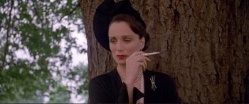 Movie still from “Richard III” (1995), directed by Richard Loncraine – A woman in a black hat smoking a cigarette next to a tree; Close Up shot, Low angle