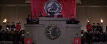 Movie still from “Richard III” (1995), directed by Richard Loncraine – A group of men standing in front of a podium; Wide shot, Low angle