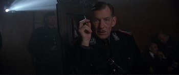 Movie still from “Richard III” (1995), directed by Richard Loncraine – A man in a military uniform holding a cell phone to his ear; Close Up shot, Low angle