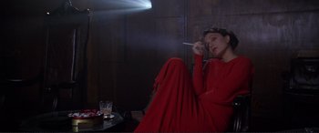 Movie still from “Richard III” (1995), directed by Richard Loncraine – A woman in a red dress smoking a cigarette; Medium shot, High angle