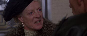 Movie still from “Richard III” (1995), directed by Richard Loncraine – An older woman wearing a black hat and a fur coat; Close Up shot, Over the shoulder angle