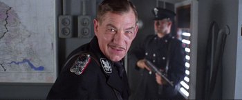 Movie still from “Richard III” (1995), directed by Richard Loncraine – A person wearing a uniform and holding a gun; Close Up shot, Low angle