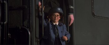 Movie still from “Richard III” (1995), directed by Richard Loncraine – A young boy wearing a helmet and a suit; Medium shot, Low angle