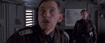 Movie still from “Richard III” (1995), directed by Richard Loncraine – An older man in military fatigues looking at the camera; Close Up shot, Low angle