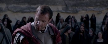 Movie still from “Risen” (2016), directed by Kevin Reynolds – A group of people standing around a man with blood all over his face; Close Up shot, Over the shoulder angle