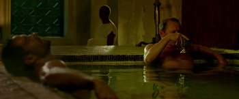 Movie still from “Risen” (2016), directed by Kevin Reynolds – A man sitting in a pool of water next to another man; Medium shot, High angle