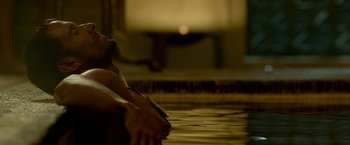 Movie still from “Risen” (2016), directed by Kevin Reynolds – A person in the water in a room with a television; Medium shot, High angle