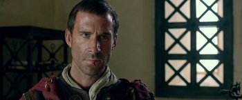 Movie still from “Risen” (2016), directed by Kevin Reynolds – A person wearing a suit; Close Up shot, Over the shoulder angle