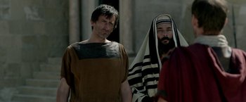 Movie still from “Risen” (2016), directed by Kevin Reynolds – A man in a robe stands next to another man in a robe; Medium shot, Over the shoulder angle