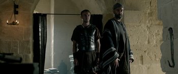 Movie still from “Risen” (2016), directed by Kevin Reynolds – Two men dressed in ancient roman clothing standing next to each other; Medium shot, Low angle