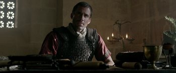 Movie still from “Risen” (2016), directed by Kevin Reynolds – A man sitting at a table in front of candles; Close Up shot, Over the shoulder angle