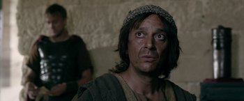 Movie still from “Risen” (2016), directed by Kevin Reynolds – A person wearing a hat; Close Up shot, Over the shoulder angle