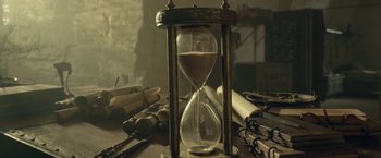 Movie still from “Risen” (2016), directed by Kevin Reynolds – An hourglass sitting on top of a wooden table; Extreme Close Up shot, High angle