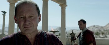 Movie still from “Risen” (2016), directed by Kevin Reynolds – A man standing in front of a fire pit; Close Up shot, Over the shoulder angle