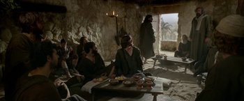 Movie still from “Risen” (2016), directed by Kevin Reynolds – A group of people sitting around a table with bowls of food; Wide shot, Over the shoulder angle
