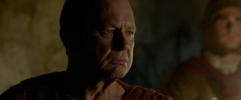 Movie still from “Risen” (2016), directed by Kevin Reynolds – An old man with a bald head is looking at the camera; Close Up shot, Low angle