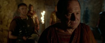 Movie still from “Risen” (2016), directed by Kevin Reynolds – A person with a fire in the background; Close Up shot, Over the shoulder angle