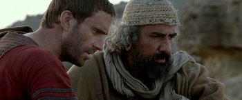 Movie still from “Risen” (2016), directed by Kevin Reynolds – Two men are talking to each other outside; Close Up shot, Over the shoulder angle