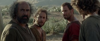Movie still from “Risen” (2016), directed by Kevin Reynolds – A group of men standing next to each other in the desert; Medium shot, Over the shoulder angle