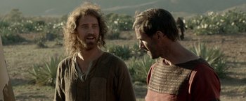 Movie still from “Risen” (2016), directed by Kevin Reynolds – Two men talking to each other while standing in a field; Close Up shot, Over the shoulder angle